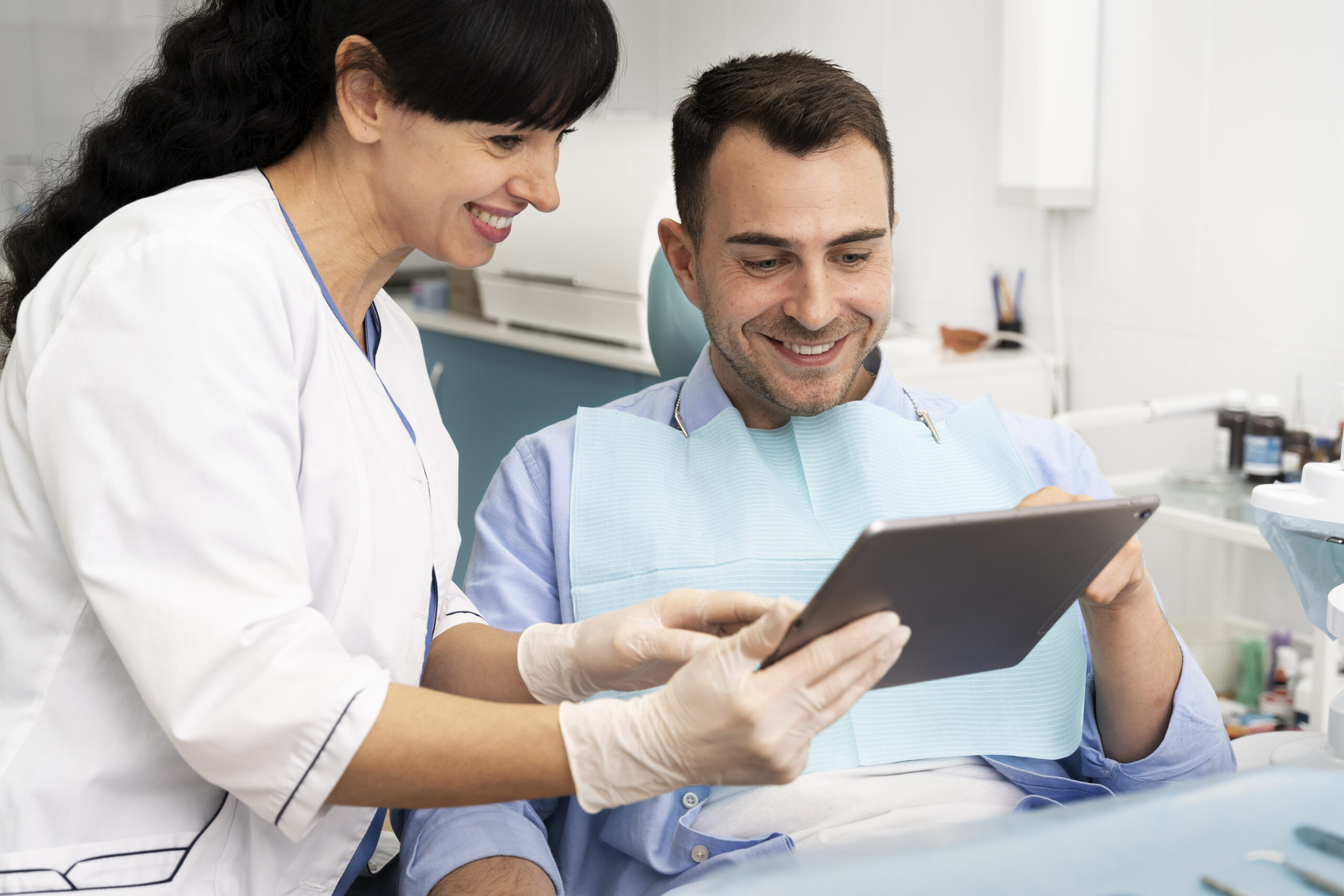 Dentist explaining treatment on a tablet to a smiling patient