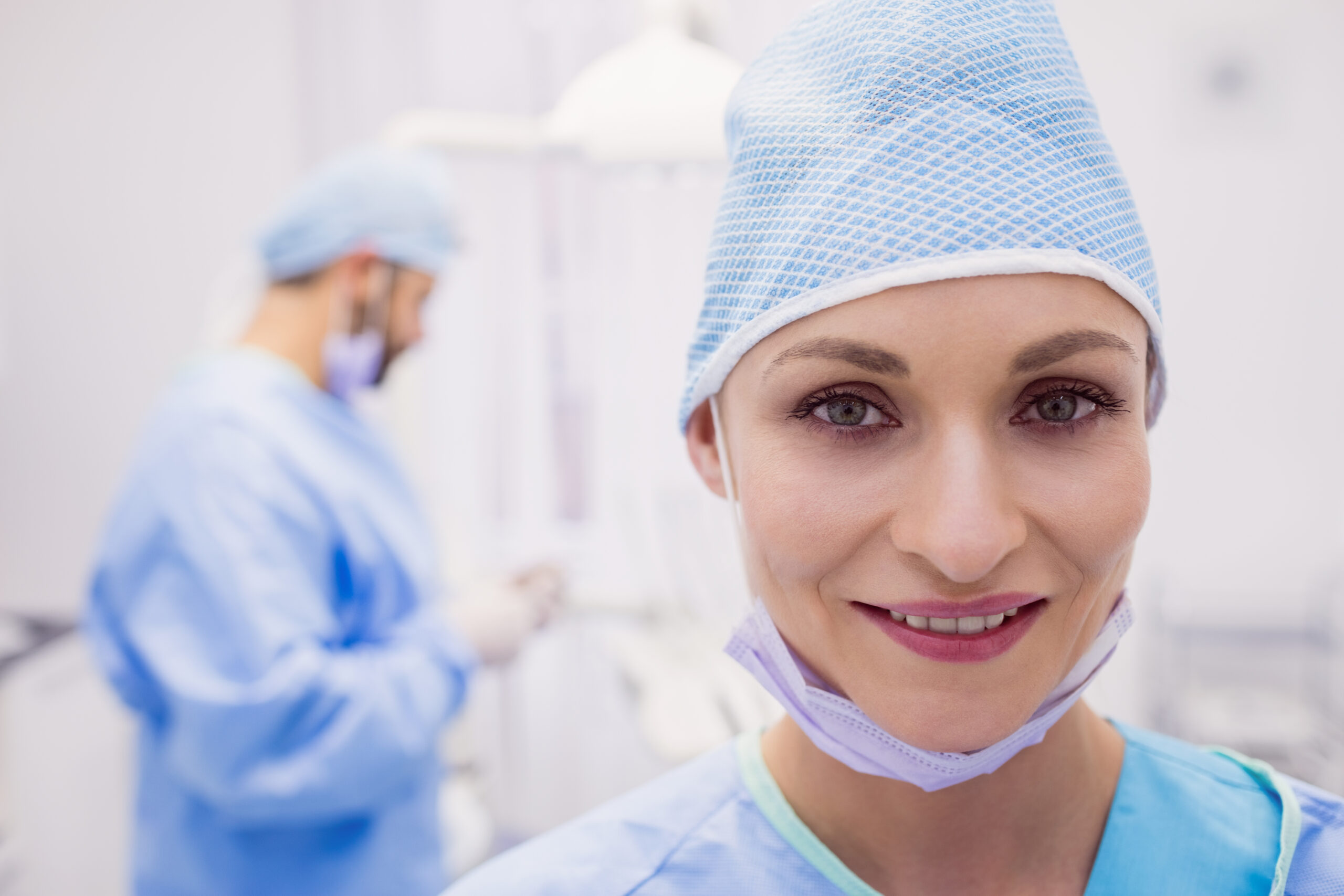 Dentist in a surgical cap with her mask lowered in the treatment room